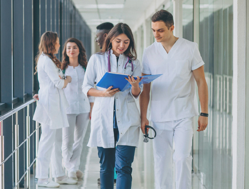 Doctors conversing while looking over a chart and walking down a hallway